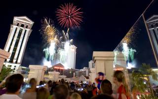 People watch fireworks over Caesars palace from a pedestrian bridge over the Las Vegas Strip on Sunday, July 4, 2010.