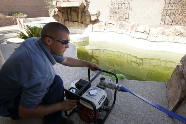 Steve Thompson of Blue Wave Pool Service drains a pool July 19 at a foreclosed home in Henderson. Many foreclosed homes have maintenance problems after residents leave.