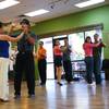 Instructor Carlos Parreno, 25, partners with Valerie Kim, 28, teaching salsa steps to students participating in a beginning salsa class Tuesday at Dance Charisma school.