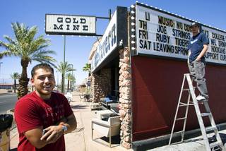 Bar manager Jose Rivera, left, and bartender Nathan Rincon update the Gold Mine Tavern's sign last week on Water Street in Henderson.