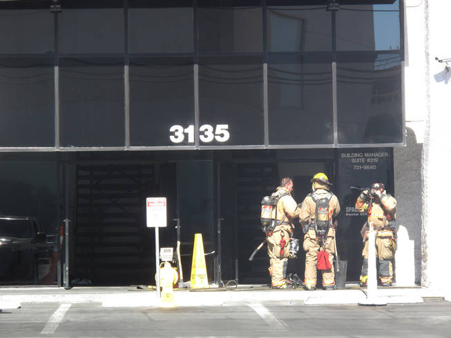 Firefighters prepare to enter a commercial building that caught fire Friday morning on Industrial Road. One woman was injured and brought to an area hospital.