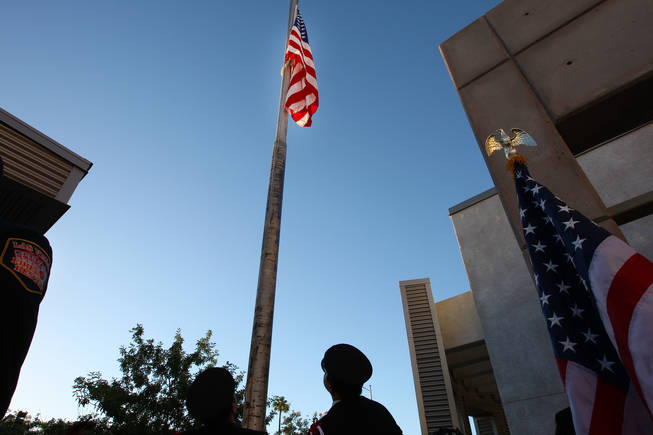 Firefighter/paramedic Joseph Digaetano and firefighter Nick Celeste, right, gaze upon the World Trade Center flag as it reaches half-staff in honor of those who died in the Sept. 11 attacks during a tribute service at Fire Station 5 in Las Vegas, Sept. 11, 2010.