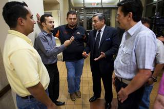 Latinos, including Emmanuel Corales, center left, Marco Hernandez, center, and Fernando Romero, president of Hispanics in Politics, talk following a community meeting Tuesday at the East Las Vegas Community Center. The meeting was held to address concerns following immigration raids in July at local bus stations.