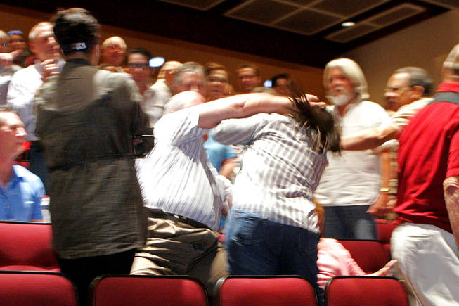 An unidentified Sharron Angle supporter punches Kay Mehta after he allegedly tried to shove Kelly Tanaka, left, over a seat after a Senate candidate forum for Angle and Reid at Faith Lutheran High School