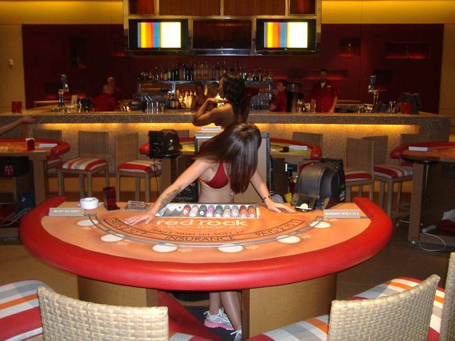 A blackjack dealer seems to be concerned about what the monitors are airing 30 minutes before the doors open for the Train show at Sandbar.