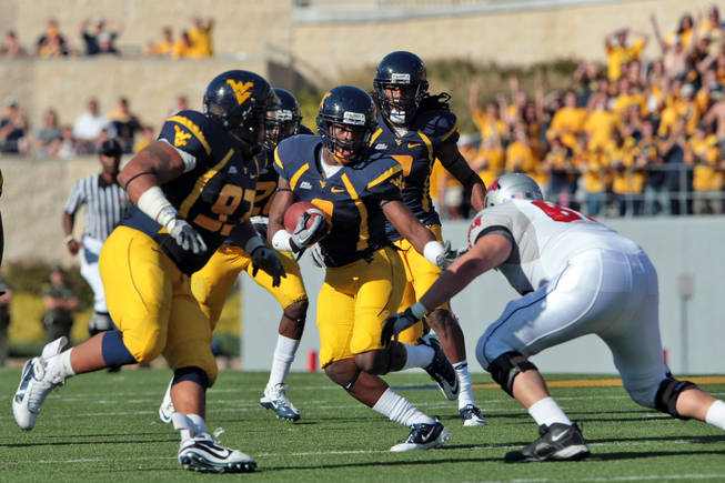 West Virginia's Keith Tandy tries to avoid being tackled by UNLV's John Gianninoto, right,  after an interception during an NCAA college football game in Morgantown, W.Va., Saturday, Oct. 9, 2010. At left is West Virginia's Scooter Berry (93). West Virginia defeated UNLV 49-10. 