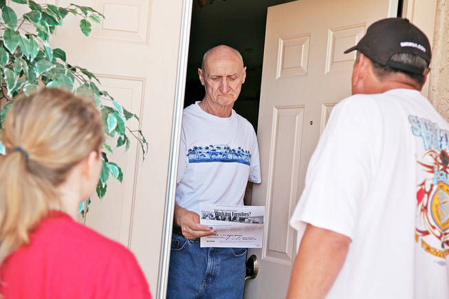 Bruno Santarosa, 64, a retiree who lives in Henderson, receives campaign literature from father-and-daughter canvassing team Randy Soltero of the United Steelworkers Union and Madeline Johnston of the Labor 2010 campaign. Santarosa says he'll definitely vote. 