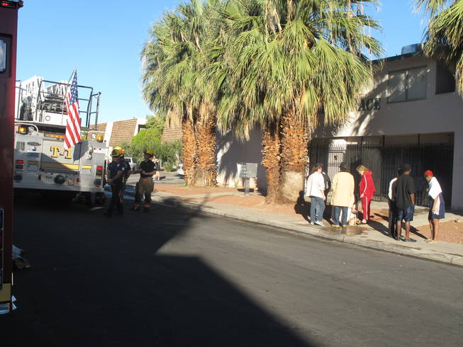 Residents gather outside a Palm Terrace Apartments complex after a morning fire gutted one unit and caused heavy smoke damage to an adjoining unit. Officials said a domestic dispute led to the fire and charged a man and woman with arson.