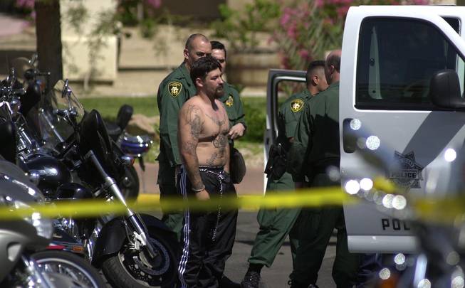 An unidentified man waits his turn to board a police van outside Harrah's Hotel and Casino on April 27, 2002, in Laughlin. Three people were killed in an early-morning shooting at the casino as rival biker gangs clashed with knives and guns. 