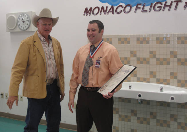 Clark County Commissioner Tom Collins, left, honors Christopher McEntire on Thursday for his actions when a student held his secretary hostage at knifepoint in September.
