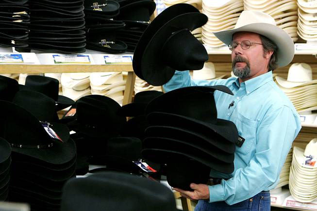 Boot Barn salesman Michael Hull looks through cowboy hats for Las Vegas Sun columnist John Katsilometes as he gets outfitted for the National Finals Rodeo on Wednesday, Nov. 24, 2010.
