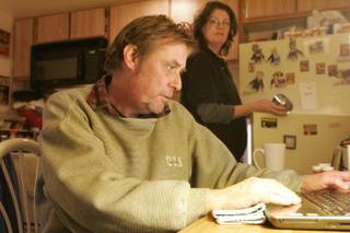 Rodger Jacobs checks his email while Lela Michael works on getting dinner ready in their apartment Thursday, December 2, 2010.