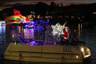 Santa Claus waves to those gathered on the shore Saturday for the annual Festival of Lights boat parade at The Lakes.