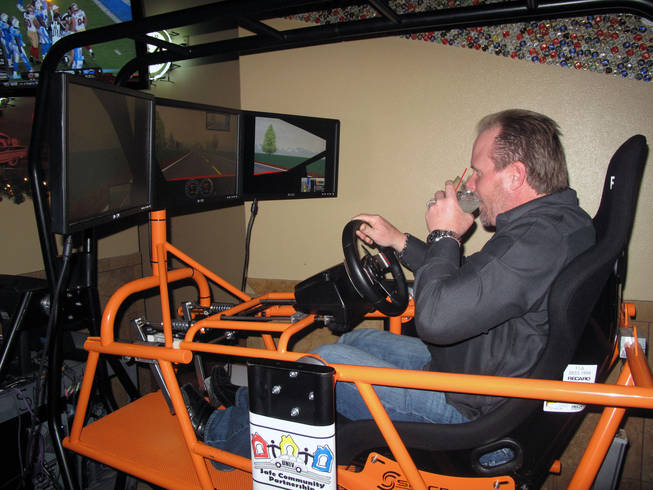 John Dlouhy takes a sip of a drink while driving a simulator at the T-Bird Lounge on Eastern Avenue Friday to demonstrate the effects alcohol has on driving. Police are planing extra patrols and DUI checkpoints over the next two weeks for the holidays.