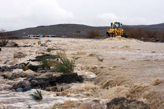 A Nevada Department of Transportation front loader keeps debris from building up as rain run-off washes over the roadway on State Route 159 near Calico Basin Dec. 22, 2010.