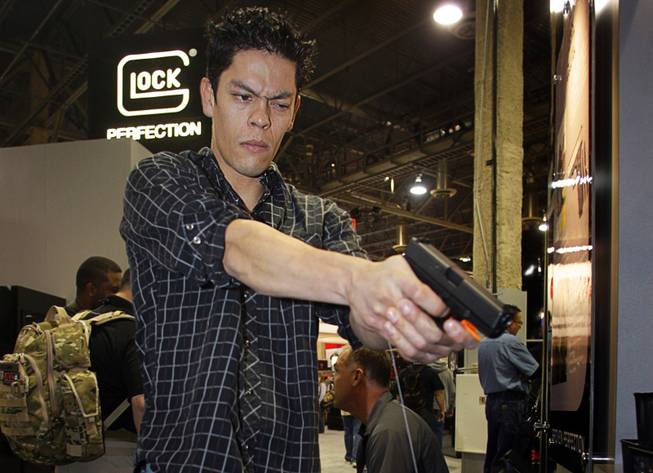 Jorge Molina, 30, of Las Vegas, aims a Glock Generation 4 Model 23 semiautomatic handgun during the National Shooting Sports Foundation's 33rd annual Shooting, Hunting and Outdoor Trade (SHOT) Show at the Sands Expo & Convention Center on Wednesday, Jan. 19, 2011.