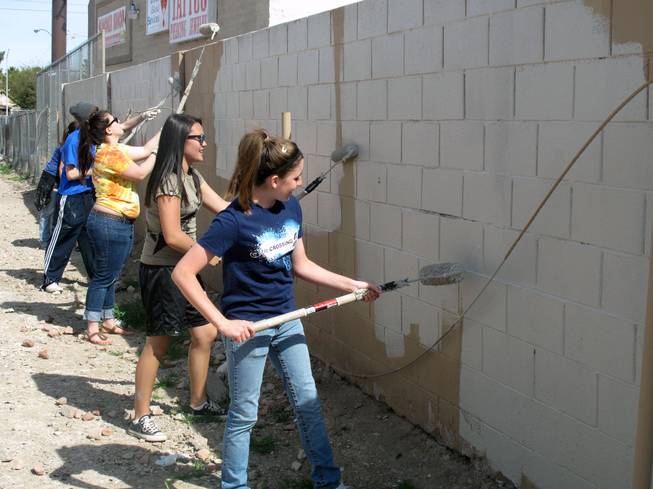 Ashlee Coate, right, and Chloe Jones, both 15, clean up graffiti Saturday morning near U.S. 95 and Charleston Boulevard along with other participants of a student ministry at the Crossings Christian Church.