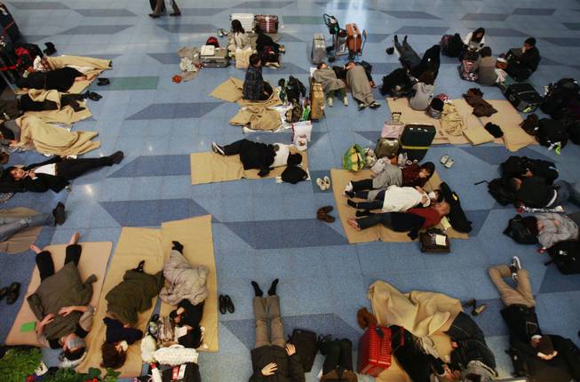 Travelers rest on the floor stranded at the Haneda international airport in Tokyo after a massive earthquake Friday, March 11, 2011. The ferocious tsunami spawned by one of the largest earthquakes ever recorded slammed Japan's eastern coasts. 