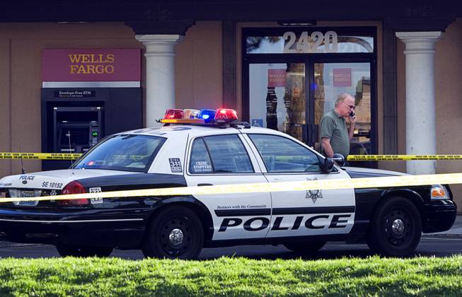 An investigator walks by the front of a Wells Fargo Bank at the corner of Sunset Road and Eastern Avenue after a robbery attempt and shooting Wednesday, March 30, 2011. 