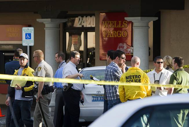 Investigators confer after a robbery attempt and shooting outside a Wells Fargo Bank at the corner of Sunset Road and Eastern Avenue on Wednesday, March 30, 2011. 