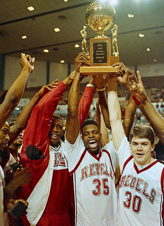 UNLV players hold their Big West trophy high over their heads in jubilation after beating California State University-Long Beach, to win the tournament in Long Beach, Calif., March 11, 1990.  Left to right are Barry Young, Moses Scurry (35) and Dave Rice.  