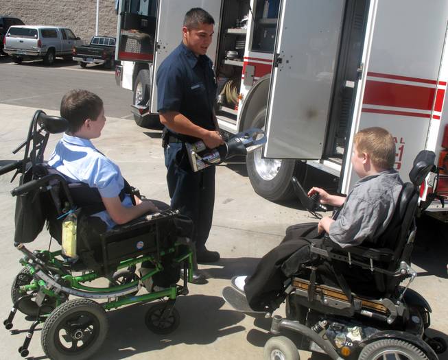 A Henderson firefighter shows 13-year-old Ian Preston, left, and 11-year-old Kyle Preston, right, tools the fire crews use while at emergency scenes. The brothers, who have Duchenne muscular dystrophy, attended the kickoff Tuesday of the 52nd annual Fill-the-Boot drive for the Muscular Dystrophy Association.