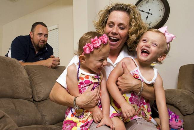 Geoff Walker, an English teacher and assistant football coach at Foothill High School, looks on as his wife, Shelby Walker, a geography teacher at Mannion Middle School, plays with twins Colbie, left, and Kenna, 3, at their home in Henderson on Thursday, June 2, 2011.