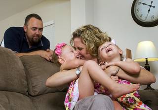 Geoff Walker, an English teacher and assistant football coach at Foothill High School, looks on as his wife Shelby Walker, a geography teacher at Manion Middle school, plays with twins Colbie, left, and Kenna, 3, at their home in Henderson Thursday, June 2, 2011.