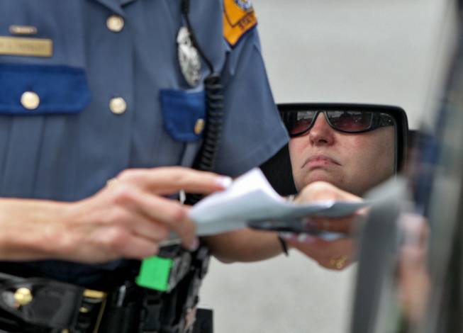 Washington State Patrol trooper Brandy Kessler checks a driver's registration before issuing her a $124 ticket for driving while talking on a cell phone Thursday, June 10, 2010, in South Hill, Wash. The Nevada Legislature passed a similar law banning the use of cell phones while driving.