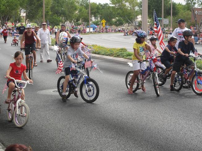 A group of children riding bikes and scooters adorned with American flags help kick off Summerlin's 17th annual Patriotic Parade as part of the parade's escort division.
