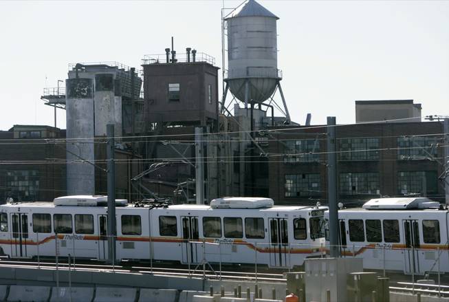 Headed south toward Denver's burgeoning suburbs, a Regional Transportation District light rail train passes in the shadow of the empty Gates Rubber Company plant in south Denver on Sunday, Nov. 19, 2006.