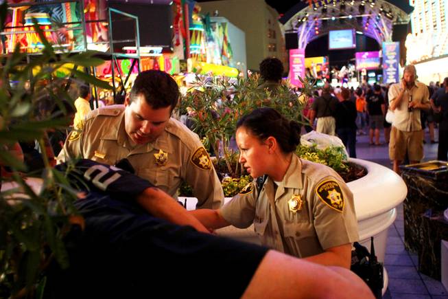 Metro Police Officers Rachel Calderon and Bryce Jones wake a man who was asleep during the pair's shift patrolling Fremont Street in downtown Las Vegas on foot Monday, Aug. 8, 2011. The patrolling is part of an initiative called Crime Free Corridor, a plan to reduce in crime in the downtown area.