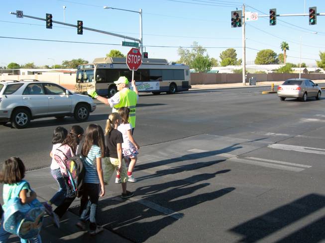 Crossing guard Paul Kmetz helps children across Christy Lane near Richard Rundle Elementary School on Tuesday.