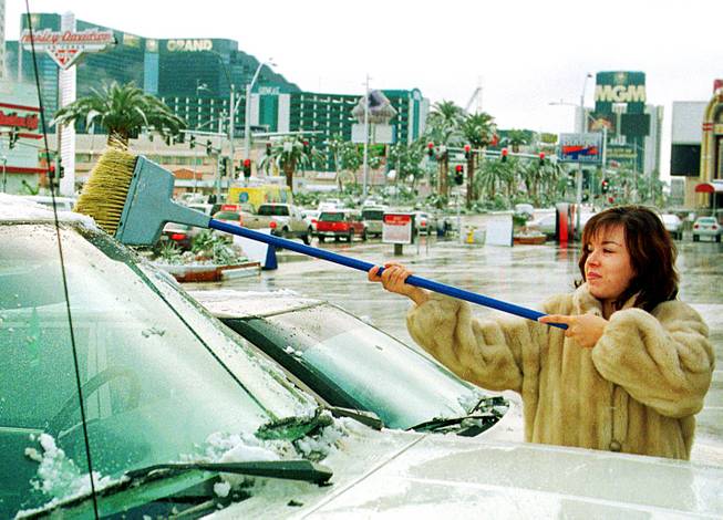 Madlen Nazrian, a UNLV student, sweeps snow off her boyfriend's truck after a rare snowstorm over the Las Vegas Strip Sunday morning, December 6, 1998. Nazrian, originally from Bulgaria, said she is used to winter weather since it snows a lot in her home country.