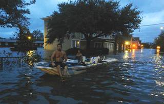 Two men use a boat to explore a street flooded by Hurricane Irene Saturday, Aug. 27, 2011 in Manteo, N.C.