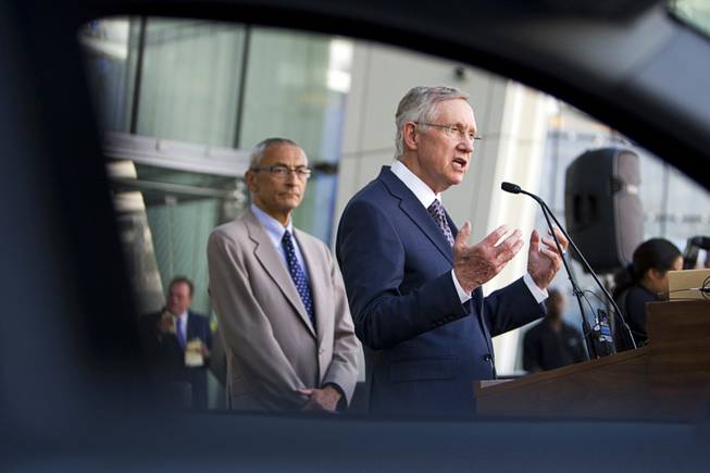 Senate Majority Leader Harry Reid (D-NV) is framed by the window of an all-electric Coda sedan as he speaks during an exhibition of alternative fuel vehicles at Aria Monday, August 29, 2011.  John Podesta, president/CEO of the Center for American Progress, listens at left.