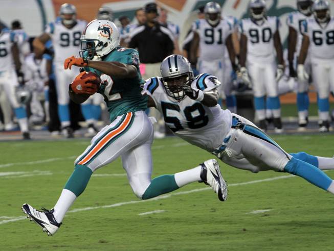 Miami Dolphins running back Reggie Bush (22) runs as Carolina Panthers linebacker Thomas Davis (58) attempts to tacke during the first half of an NFL pre-season football game Friday, Aug. 19, 2011, in Miami. 