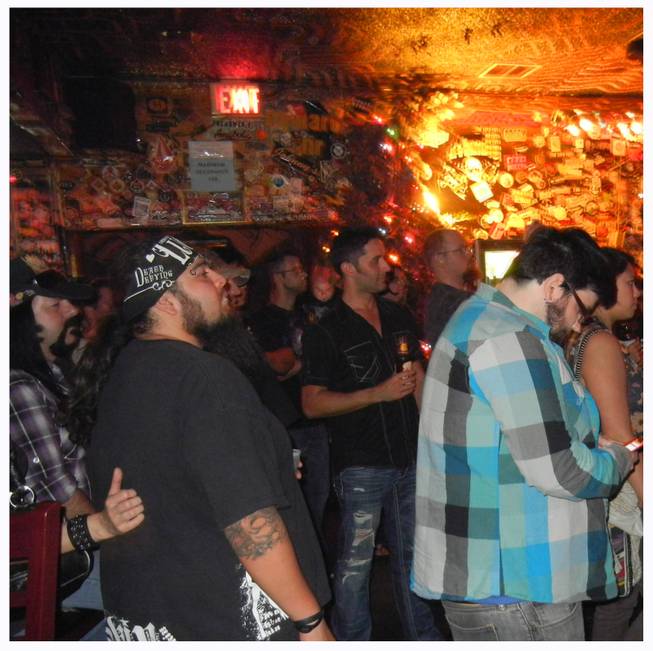 At Double Down Saloon Ryan Martin, far right in checked shirt, texts friends about being in the same club as Vinnie Paul, far left at the bar.