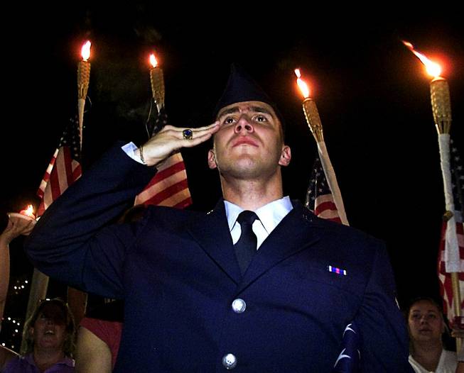 Airman 1st Class Sean Romero with the New Jersey Air National Guard, 177th Fighter Wing, salutes as the national anthem is sung during a candlelight vigil at the Thomas & Mack Center, Wednesday, Sept. 12, 2001, to honor those killed in the terrorist attacks.