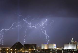 Lightning strikes behind the Luxor, left, and Excalibur hotel-casinos as a thunderstorm passes through Las Vegas early in the morning of September 11, 2011.