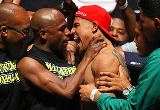 Undefeated welterweight boxer Floyd Mayweather Jr., left, grabs the throat of WBC welterweight champion Victor Ortiz as they face off during an official weigh-in at the MGM Grand Garden Arena Friday, September 16, 2011. Mayweather will challenge Ortiz for the title at the arena Saturday.