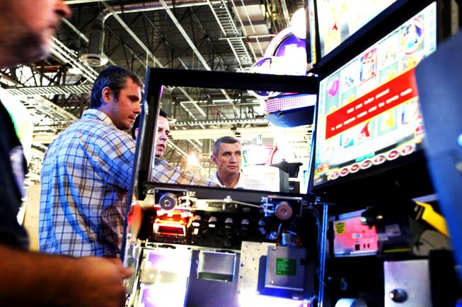 Mikhail Stepanov, from right, managing director of Octavian in St. Petersburg, Charles Hiten, managing director of Novomatic in Chile, and Alexander Nikitin head of the games development department of Octavian in St. Petersburg, go over some of the slot machines in the Novomatic booth during setup for Global Gaming Expo at the Sands Convention Center in Las Vegas Monday, October 3, 2011.