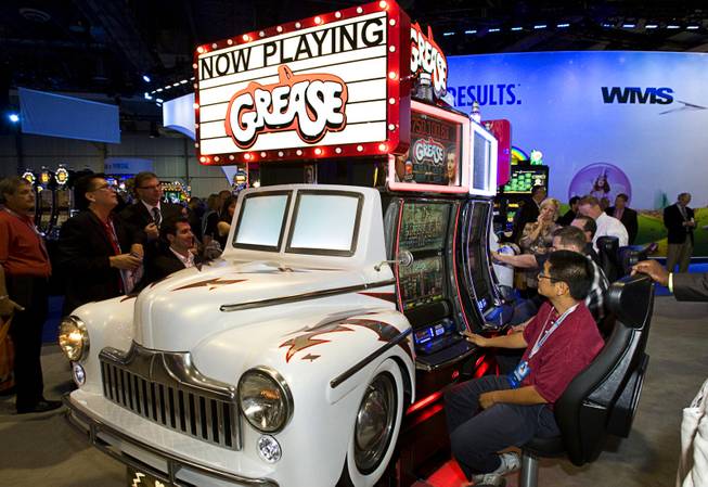 Show attendees try out Grease-themed video slot machines at a ...