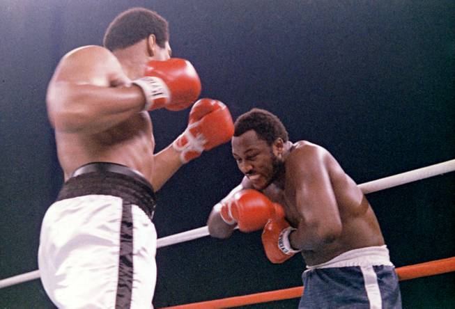 In this Oct. 1, 1975, file photo, heavyweight boxer Joe Frazier grimaces after Muhammad Ali, left, landed a blow to Frazier's head during their boxing bout in Manila, the Philippines. Ali won the fight after Frazier's manager stopped the fight in the 14th round. Frazier, the former heavyweight champion who handed Ali his first defeat yet had to live forever in his shadow, has died after a brief final fight with liver cancer. He was 67. The family issued a release confirming the boxer's death on Monday night, Nov. 7, 2011. 