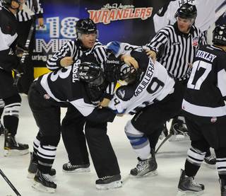 ECHL linesmen Wally Lacroix, center, and Todd Owen attempt to re-establish order after a skirmish breaks out between Las Vegas Wrangler Shawn Fensel (3) and Kael Mouillierat during the first period on Tuesday night at the Orleans Arena.