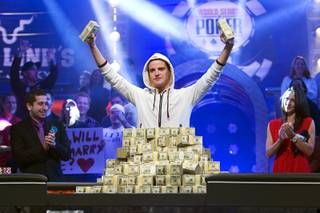 Pius Heinz of Germany holds up stacks of cash after defeating Martin Staszko of the Czech Republic to win the championship bracelet and $8.7 million in first-place prize money during the World Series of Poker Main Event early Wednesday morning, Nov. 9, 2011, at the Rio. In the background are 2010 winner Jonathan Duhamel and ESPN reporter Kara Scott.