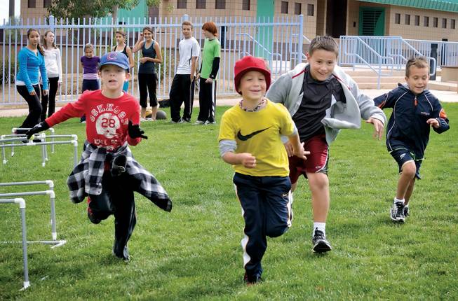 A group of boys runs to the next station of an obstacle course during home school boot camp at Centennial Hills Park.