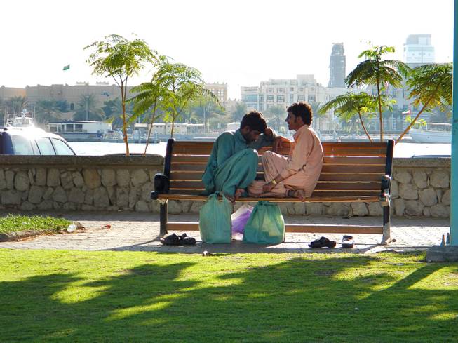 In Dubai, United Arab Emirates, two labor workers chat during their lunch break near Deira Creek. December  2011.