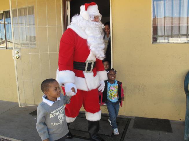 Santa surprises 3-year-old Tristina and 4-year-old Trenton Wednesday afternoon with presents from Operation Fire H.E.A.T. Their North Las Vegas home and Christmas presents were destroyed in an accidental fire Dec. 15
