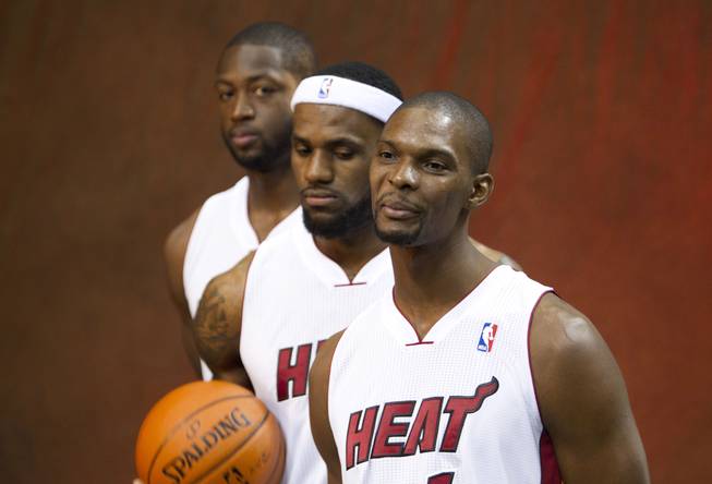In this Dec. 12, 2011, photo, Miami Heat players Dwyane Wade, back, LeBron James and Chris Bosh pose for photos during the NBA basketball team's media day in Miami. It's Act Two for the Big Three, and the Heat are bringing back almost the exact same cast for what they hope is another title shot. 